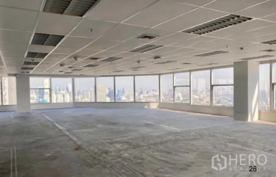 Office Space for rent in Sathon, Bangkok - Open-plan high-floor office with wraparound windows, grid ceiling, fluorescent lighting, and panoramic Bangkok skyline views.