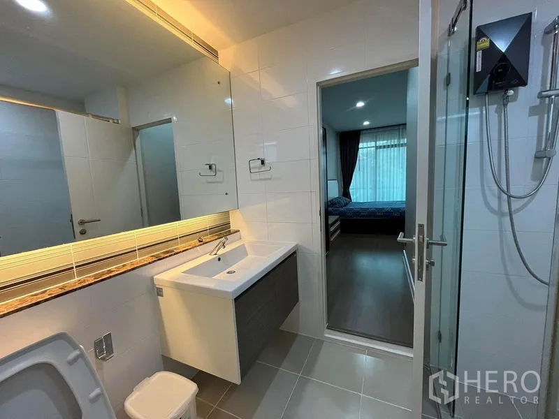 Detached House for rent in Bang Kapi, Bangkok - Bathroom vanity with large mirror next to glass shower and bedroom entry