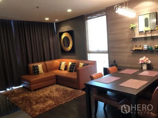 คอนโด ให้เช่าหรือขายในWatthana, Bangkok - ห้องนั่งเล่นและรับประทานอาหารโทนอุ่น โซฟาหนังตัวแอล ม่านทึบ ชั้นวาง และโคมไฟแขวน