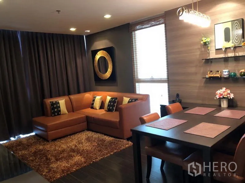 คอนโด ให้เช่าหรือขายในWatthana, Bangkok - ห้องนั่งเล่นและรับประทานอาหารโทนอุ่น โซฟาหนังตัวแอล ม่านทึบ ชั้นวาง และโคมไฟแขวน