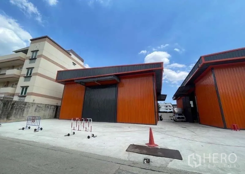 Warehouse for rent in Wang Thonglang, Bangkok - Front facade of twin modern warehouses with tall roller doors and ample forecourt parking space.