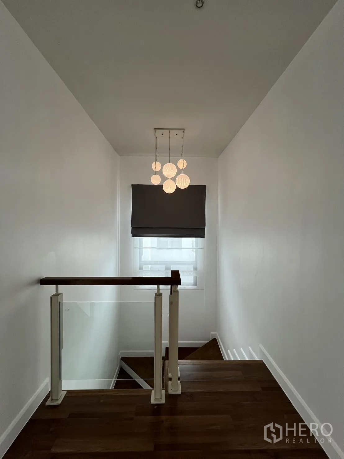 独立式住宅 出租在Bang Kapi, Bangkok - 楼梯平台，现代吊灯与玻璃扶手。
