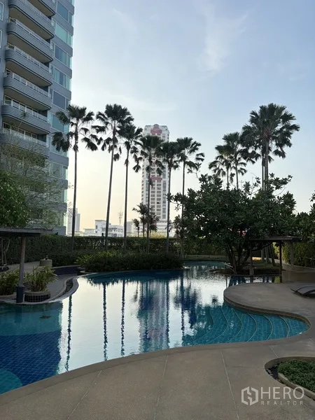 คอนโด for rent in Khlong San, Bangkok - สระว่ายน้ำรูปทรงโค้ง รายล้อมด้วยต้นปาล์มและสวนภูมิทัศน์