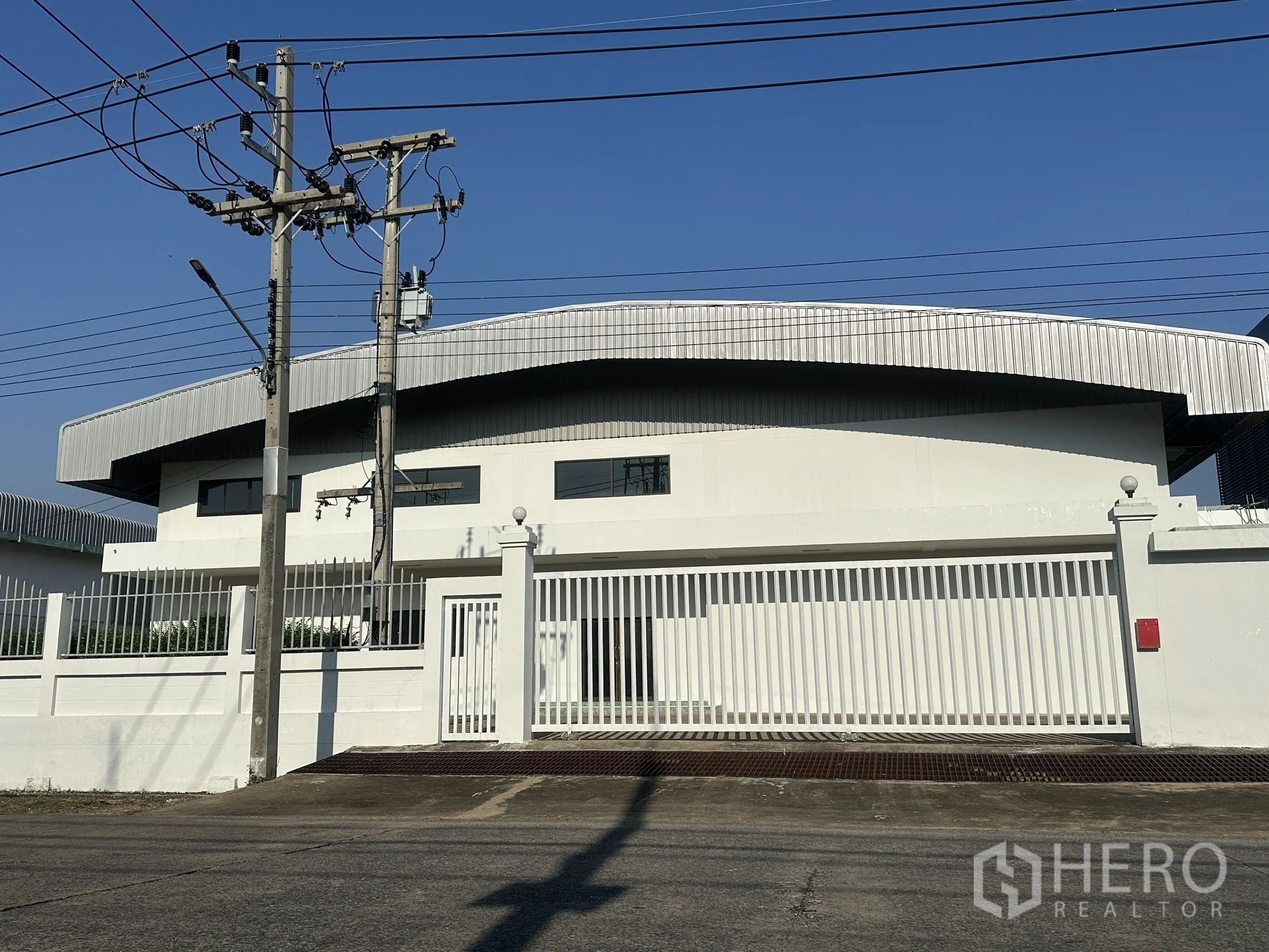 Factory for sale in Khlong Luang, Pathum Thani - Front elevation showing wide sliding metal gate and driveway ramp.