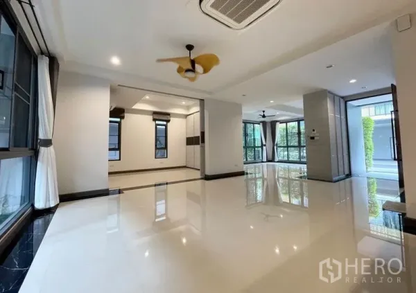 Detached House for rent in Bang Na, Bangkok - Spacious open-plan living area with glossy floors, large windows and ceiling fans.