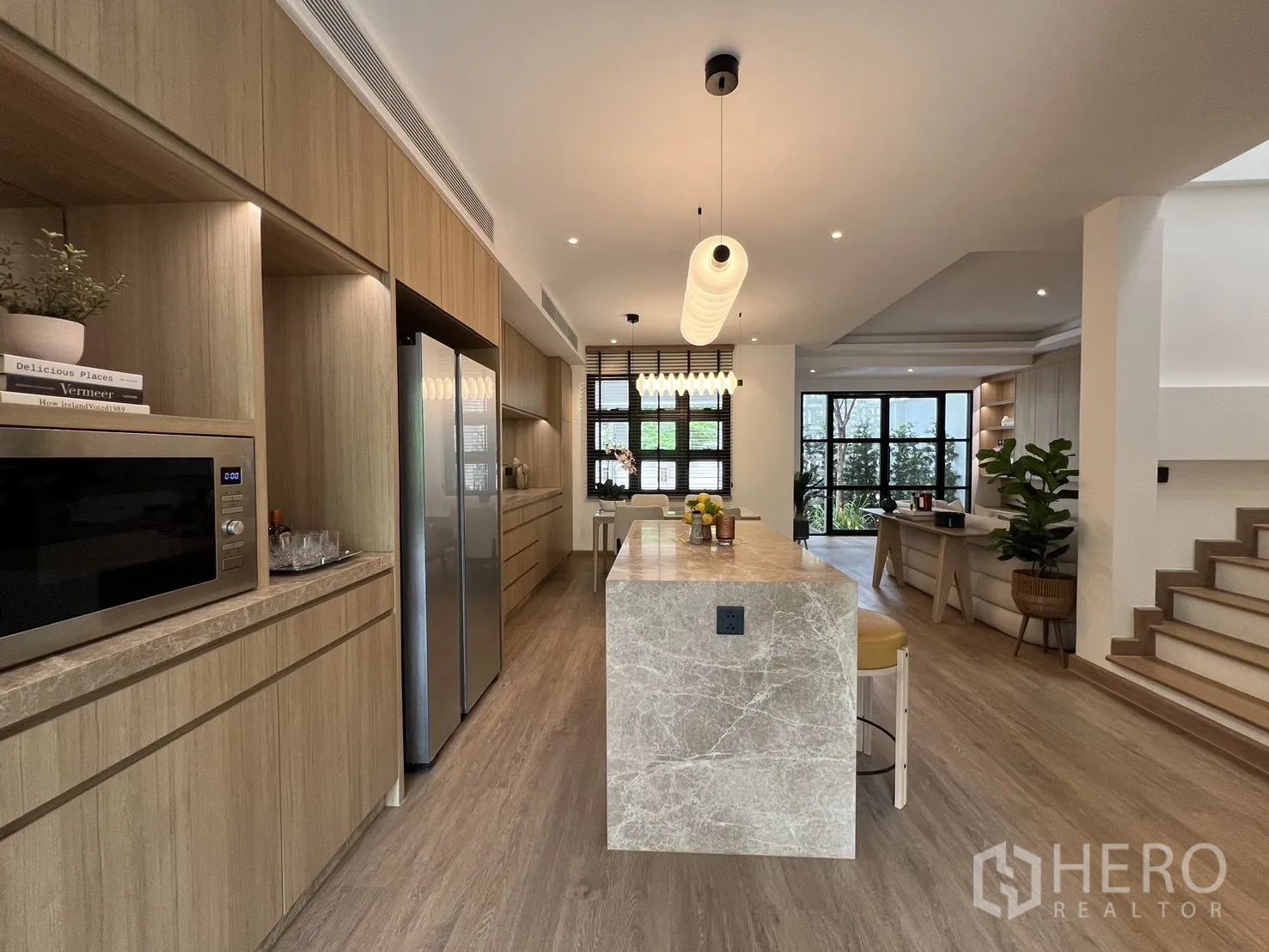 Townhouse for sale in Watthana, Bangkok - Designer kitchen featuring a long marble island, wood cabinetry and a double-door fridge.