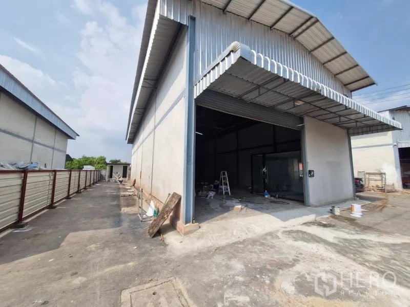 Warehouse for rent in Bang Khun Thian, Bangkok - Front exterior of metal-clad warehouse with wide roller door and truck-friendly driveway in Bang Khun Thian.