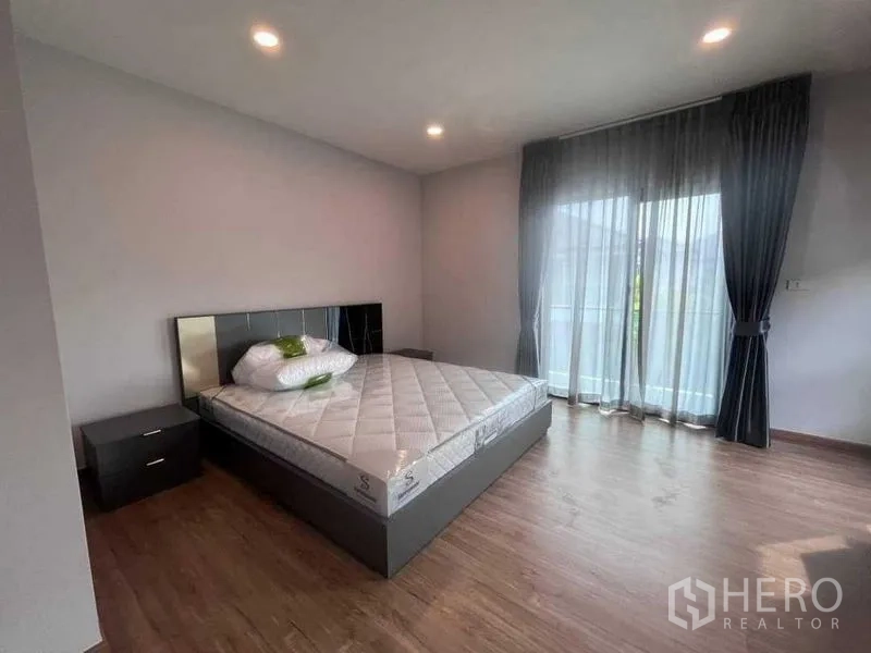 Detached House for rent in Don Mueang, Bangkok - Bright bedroom with queen bed, wood floors and sliding glass doors to a balcony.