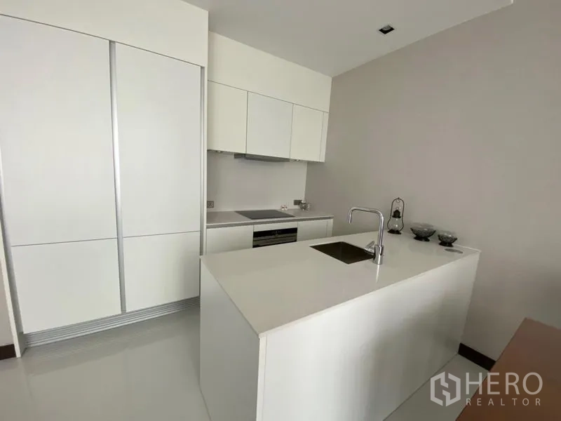 คอนโด ให้เช่าในKhlong Toei, Bangkok - ครัวสีขาวมินิมอลพร้อมไอส์แลนด์ อ่างล้างมือ เตาอบบิวท์อิน และพื้นที่เก็บของ