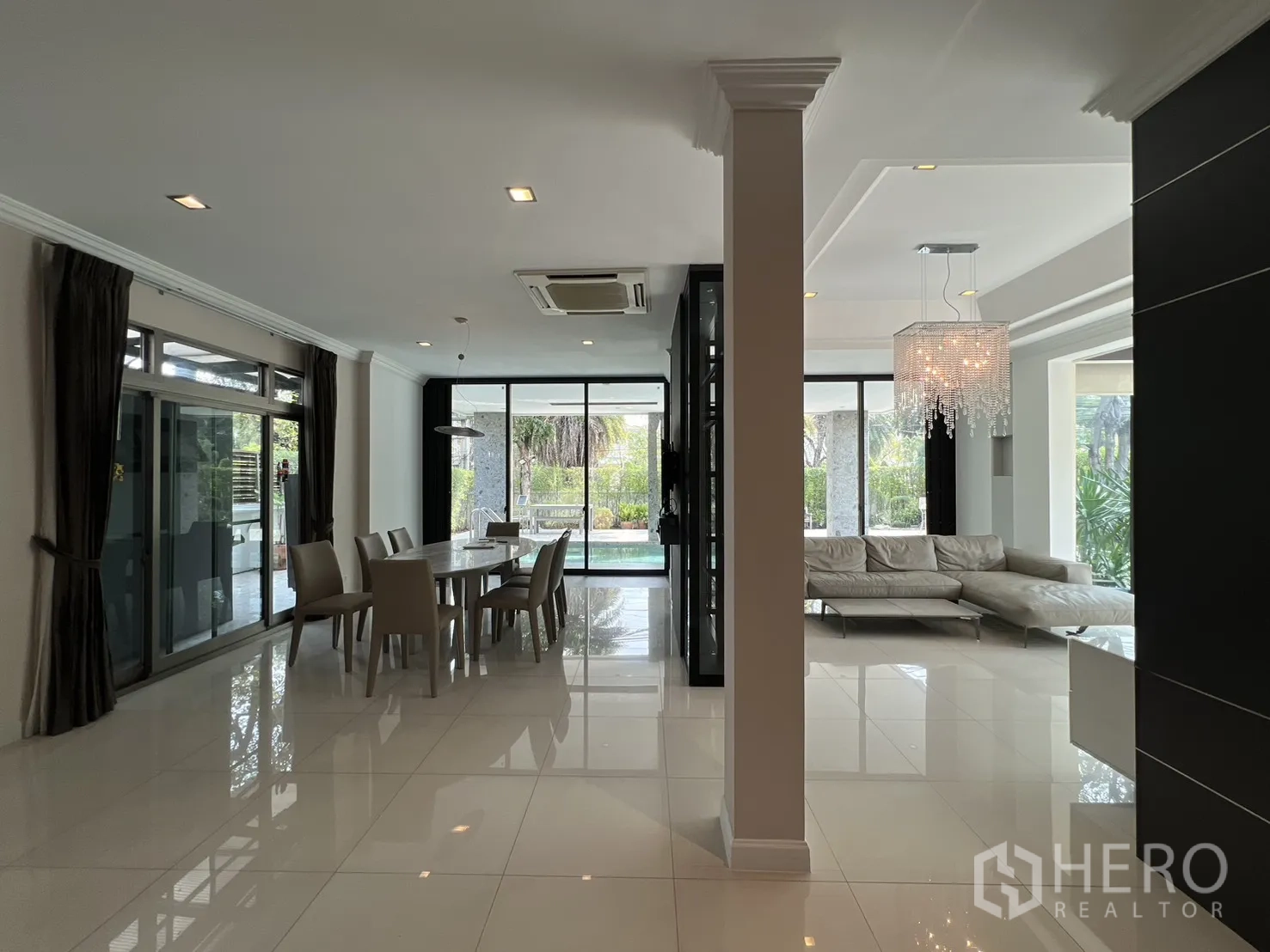 独栋房屋 for rent in Prawet, Bangkok - 开放式客餐厅，亮面地砖，通过玻璃可见泳池景观。