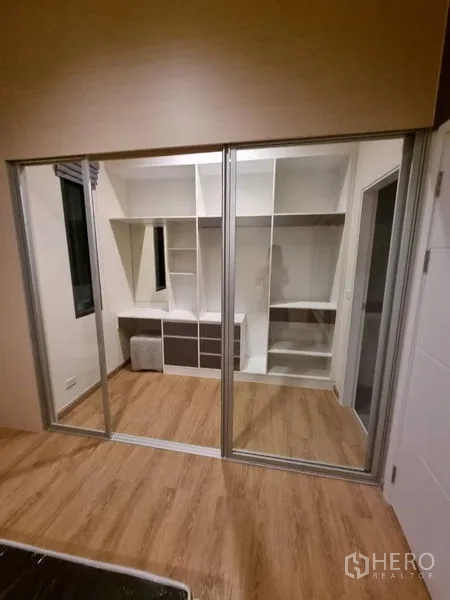 Townhouse for rent - Bedroom corner facing sliding glass wardrobe doors revealing shelves and a study desk inside.