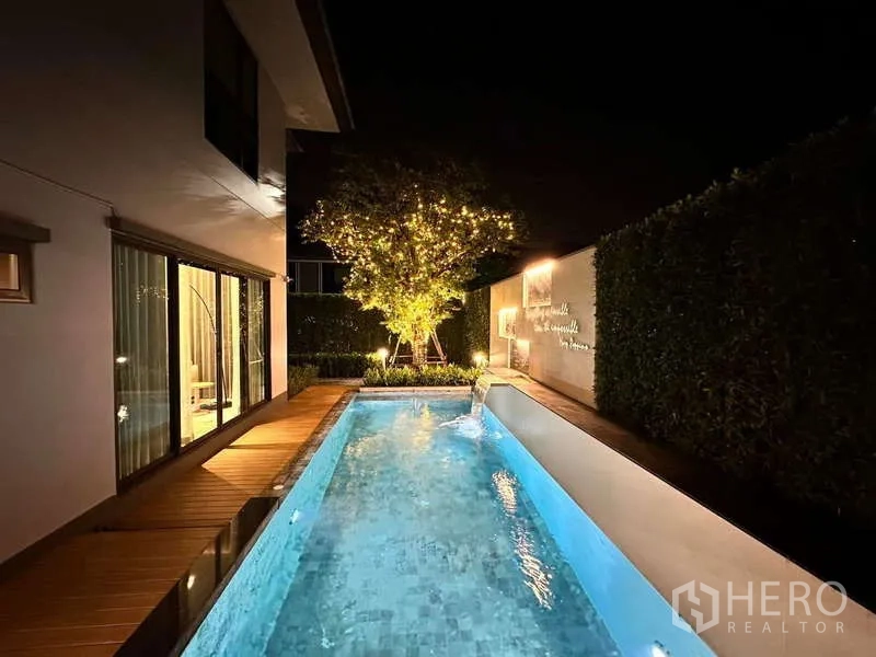 Detached House for rent or sale in Bang Kapi, Bangkok - Night view of the narrow lap pool with deck, hedge and tree lights.