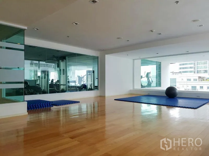 Apartment for rent in Khlong Toei, Bangkok - Spacious fitness and yoga studio with wooden floors, mirrors and mats overlooking the gym.