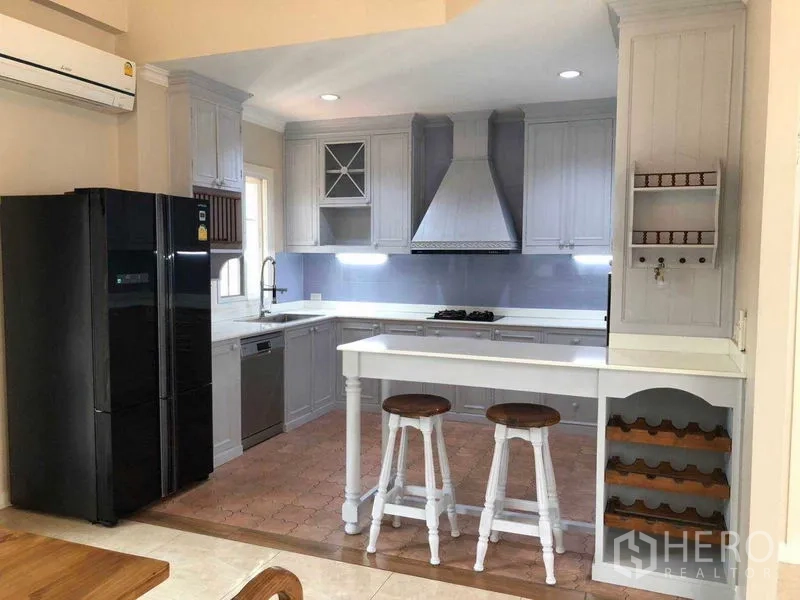 独立式住宅 出租在Bang Na, Bangkok - 整体厨房视角，吧台、酒架、黑色冰箱和洗碗机。