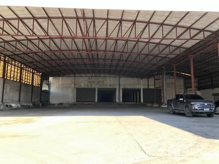 Factory for rent in Bang Phli, Samut Prakan - Wide covered loading bay with steel truss roof, roller shutters and a concrete apron at an industrial factory, pickup truck parked at the side.