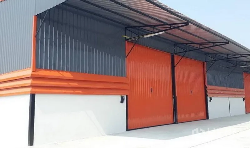Warehouse for rent in Lam Luk Ka, Pathum Thani - Row of modern warehouses with orange sliding doors and steel canopies over the loading area.