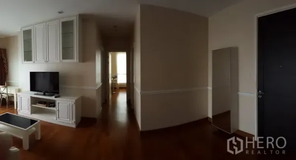 公寓 出租在Bang Rak, Bangkok - 宽敞玄关与走廊通往卧室，带电视柜与全身镜，木地板。