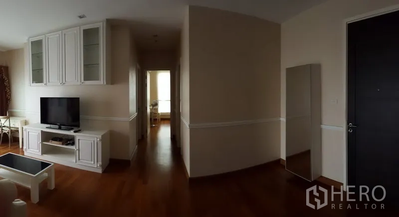 公寓 出租在Bang Rak, Bangkok - 宽敞玄关与走廊通往卧室，带电视柜与全身镜，木地板。