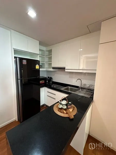 อพาร์ทเมนท์ ให้เช่าในKhlong Toei, Bangkok - ครัวบิ้วท์อินโทนขาว เคาน์เตอร์หินสีดำ ตู้เย็นขนาดใหญ่