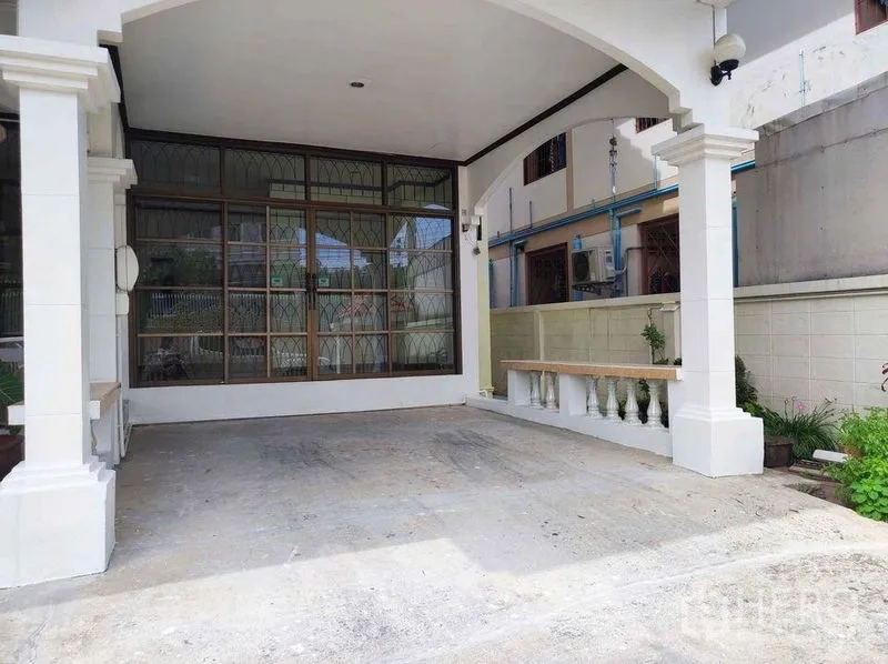 Detached House for rent in Khlong Toei, Bangkok - Covered carport with arches and pillars beside a large windowed wall, providing shaded parking.