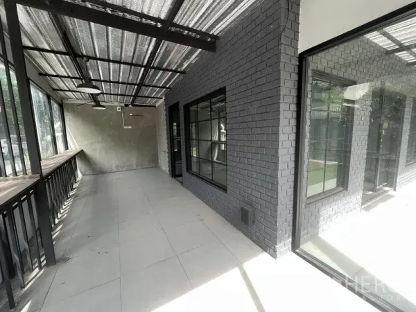 零售空间 出租在Watthana, Bangkok - 带顶棚的玻璃长廊，黑砖墙与大窗，临街采光好。