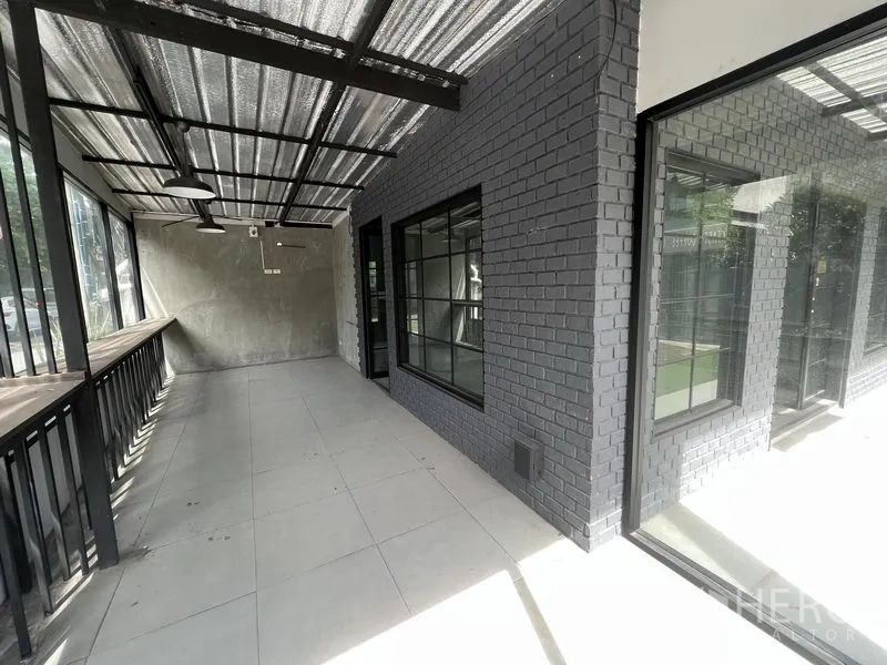 零售空间 出租在Watthana, Bangkok - 带顶棚的玻璃长廊，黑砖墙与大窗，临街采光好。
