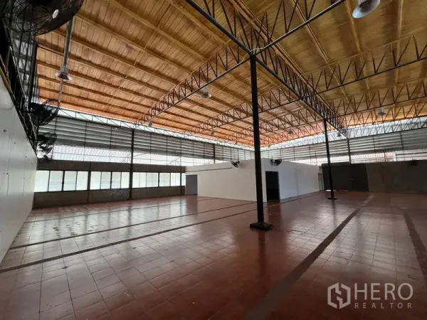 Warehouse for rent in Saphan Sung, Bangkok - Wide storage space with support columns, wall fans and abundant natural light.