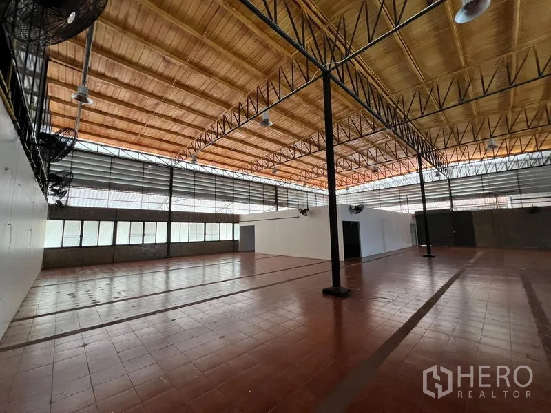 Warehouse for rent in Saphan Sung, Bangkok - Wide storage space with support columns, wall fans and abundant natural light.