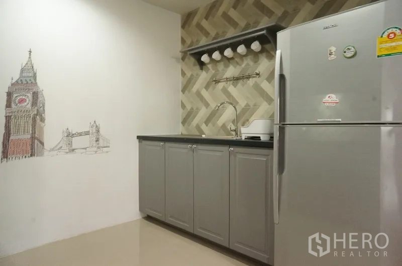 Condominium for rent in Watthana, Bangkok - Kitchen sink area with open shelf and hanging cups beside a stainless refrigerator.