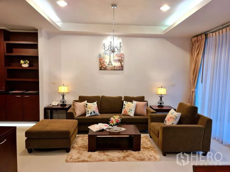 อพาร์ทเมนท์ ให้เช่า - มุมนั่งเล่นพร้อมโคมแชนเดอเลียร์ ชุดโซฟา และตู้บิวท์อิน