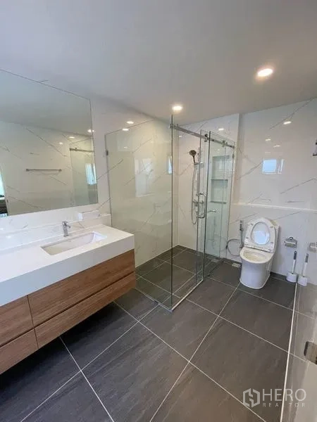 Detached House for rent in Don Mueang, Bangkok - Contemporary bathroom with glass-enclosed shower, toilet and wall-mounted vanity.