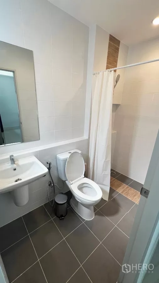 Townhouse for rent in Bang Phli, Samut Prakan - Second bathroom with shower area, mirror and gray floor tiles.