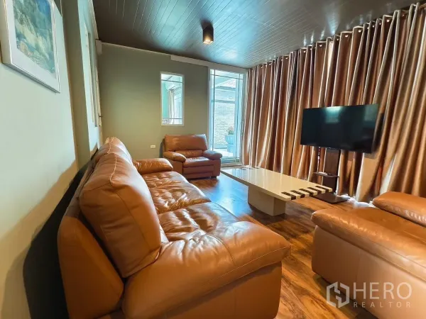 Detached House for rent in Bang Kapi, Bangkok - Cozy lounge with brown leather sofas, draped curtains and TV.