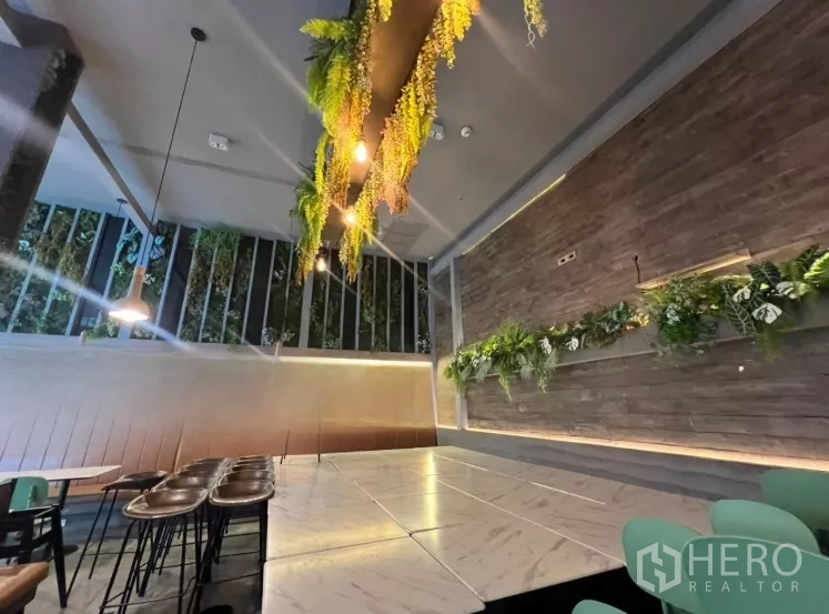 零售空间 出租 - 时尚用餐区，石纹桌面、木质特色墙与垂挂绿植，挑高天花。