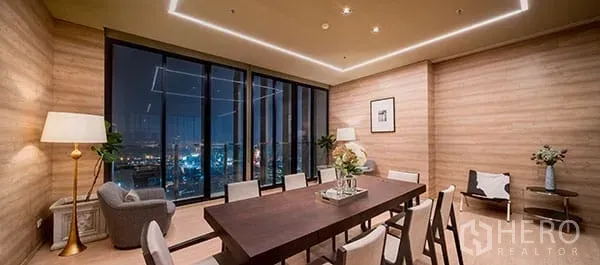 Condominium for sale in Khlong Toei, Bangkok - Residents’ lounge with a long dining table, warm wood walls, and night city views through large glass panels.
