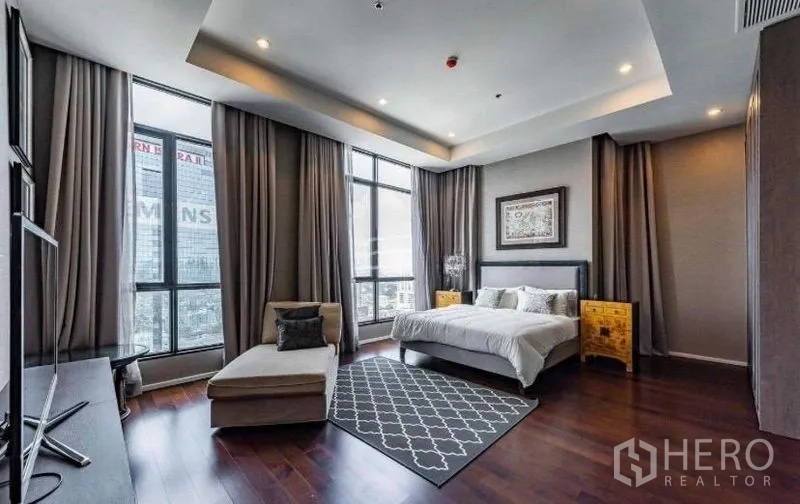 Condominium for rent - Large master bedroom with corner floor-to-ceiling windows, lounge chair and city view.