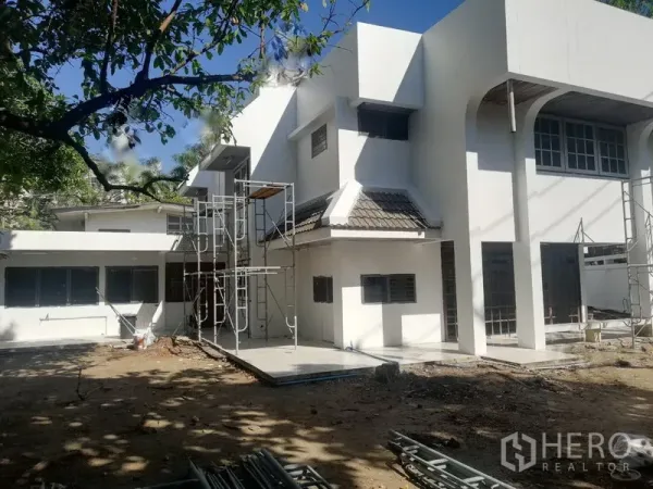 零售空间 出租在Khlong Toei, Bangkok - 建筑外立面配脚手架与宽阔庭院，树荫环绕