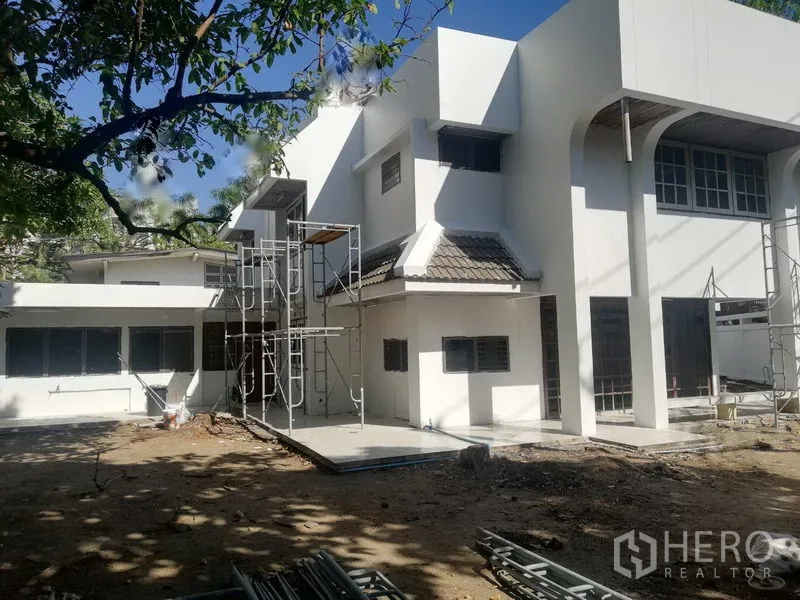 零售空间 出租在Khlong Toei, Bangkok - 建筑外立面配脚手架与宽阔庭院，树荫环绕