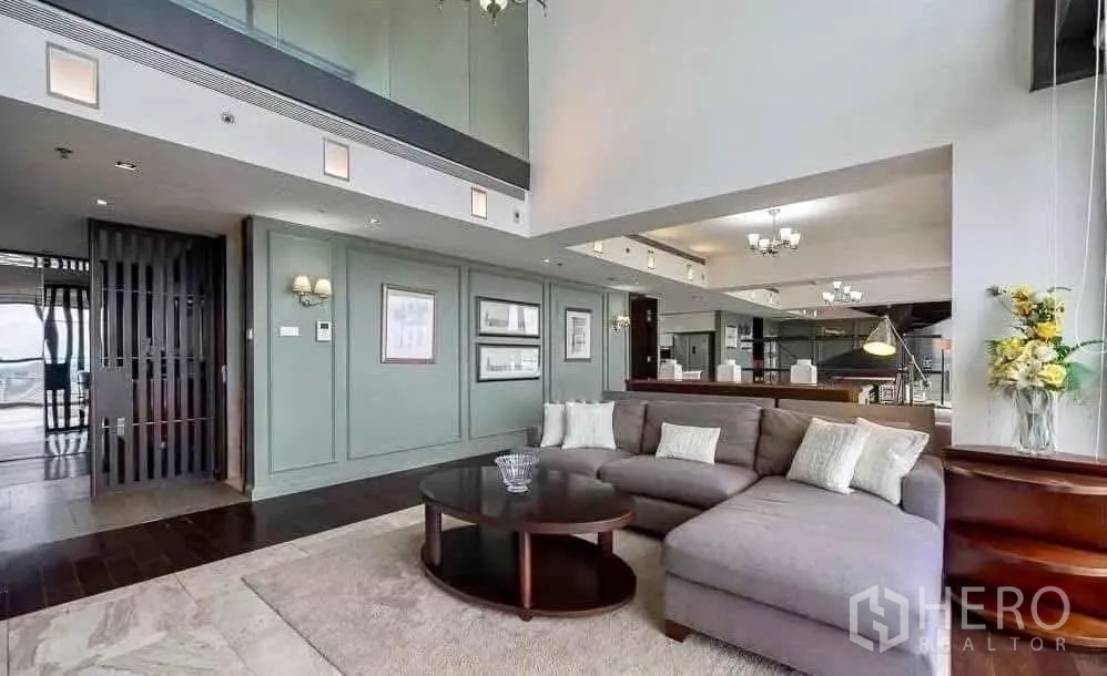 Condominium for rent in Sathon, Bangkok - Spacious living room with sectional sofa, mint wall panels and entry corridor in duplex condo.