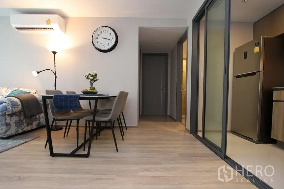 Condominium for rent in Watthana, Bangkok - Dining zone with wall clock beside sliding doors to the enclosed kitchen.