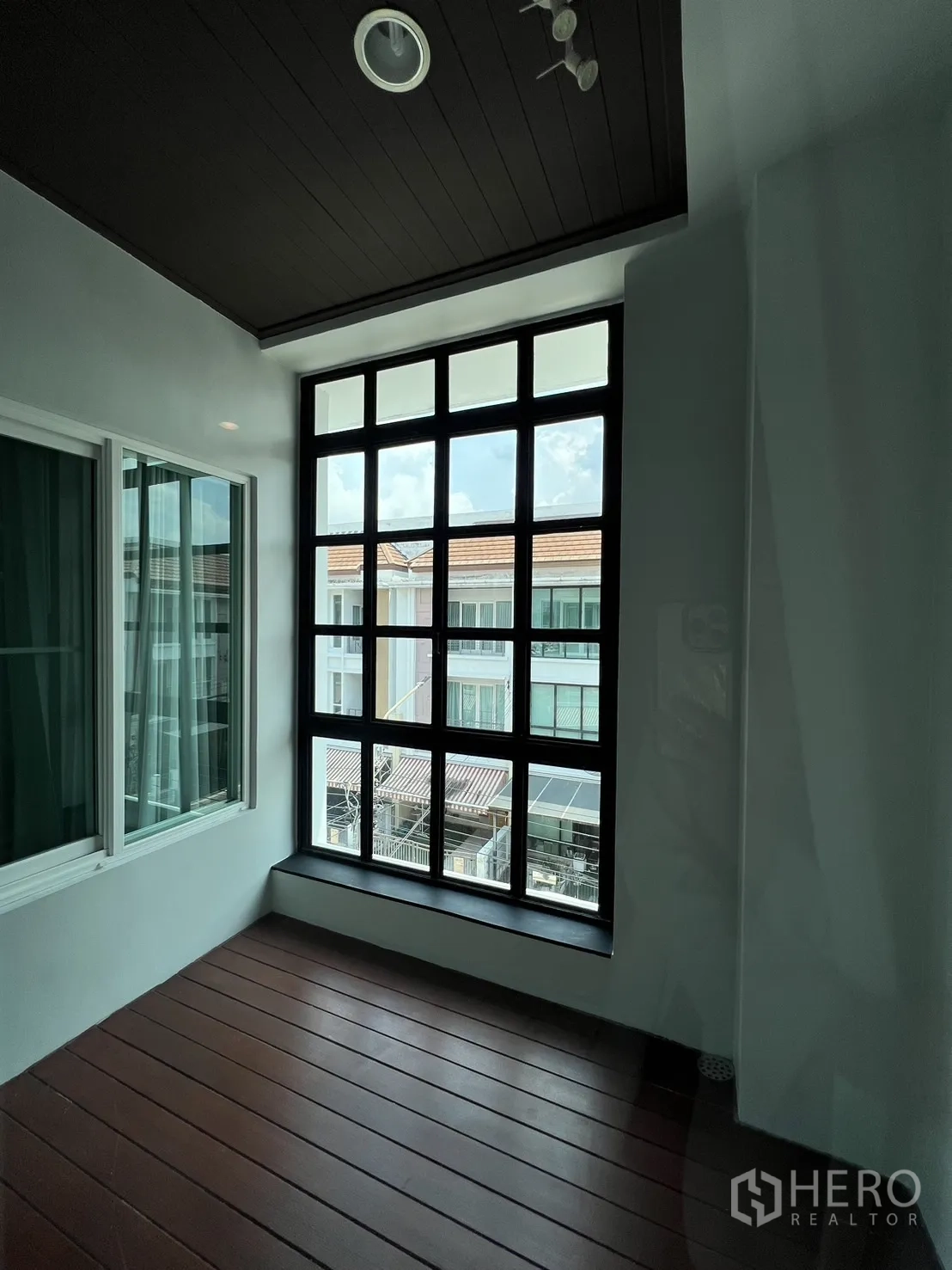 Townhouse for rent in Wang Thonglang, Bangkok - Enclosed balcony or sunroom with large grid window and wood-look floor.