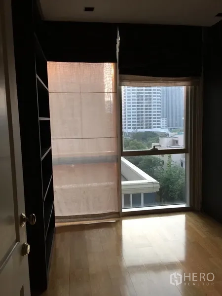 Condominium for rent in Pathum Wan, Bangkok - Bedroom window with city view and built-in shelving beside the frame.