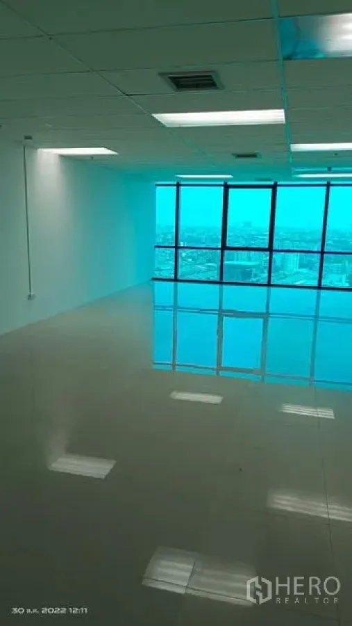 Office Space for rent in Huai Khwang, Bangkok - Open-plan office in Huai Khwang, Bangkok with glossy tiled floors, drop-ceiling lights, and blue-tinted floor-to-ceiling windows overlooking the city skyline.