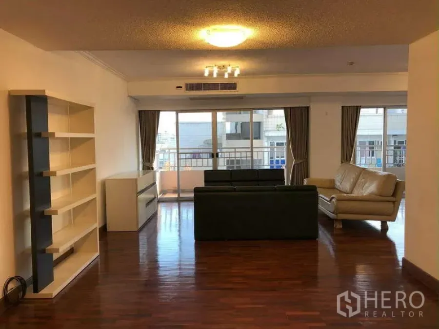 公寓 出租在Sathon, Bangkok - 宽大客厅，内置书架、皮沙发，并可通过推拉门通往阳台