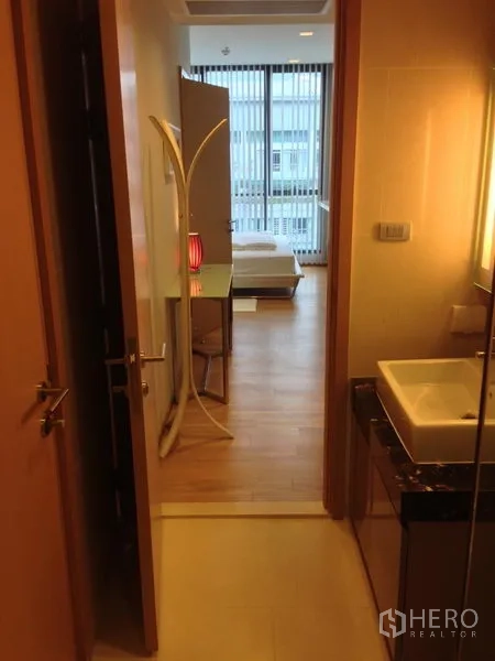 คอนโด ให้เช่าในWatthana, Bangkok - ประตูห้องน้ำมองออกไปยังโถงและห้องนอน แสงไฟอบอุ่น