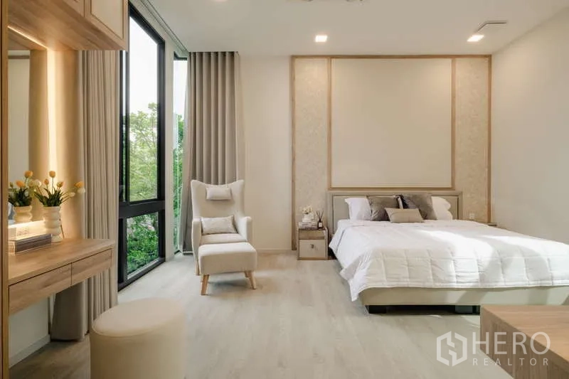 Detached House for rent in Saphan Sung, Bangkok - Bright bedroom with large windows, lounge chair, and neutral modern decor.