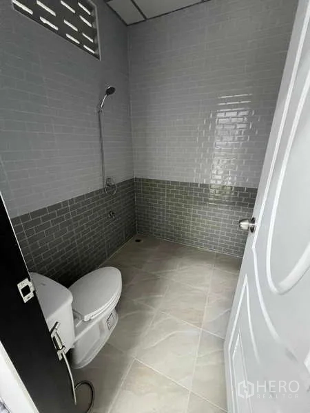 Warehouse for rent in Phra Samut Chedi, Samut Prakan - Clean restroom with gray wall tiles, shower area, and toilet inside the warehouse.
