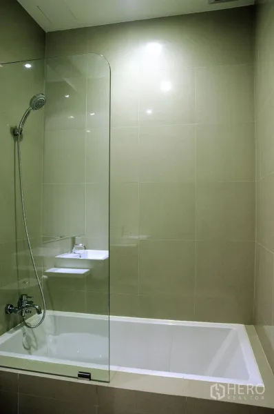 Condominium for rent in Watthana, Bangkok - Bathroom featuring a built-in bathtub with glass screen and handheld shower.