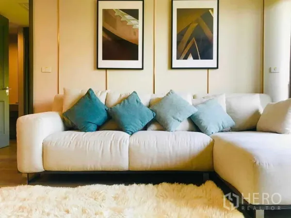 Condominium for rent - Bright living room with cream L-shaped sofa, blue cushions, framed artwork and a plush rug.