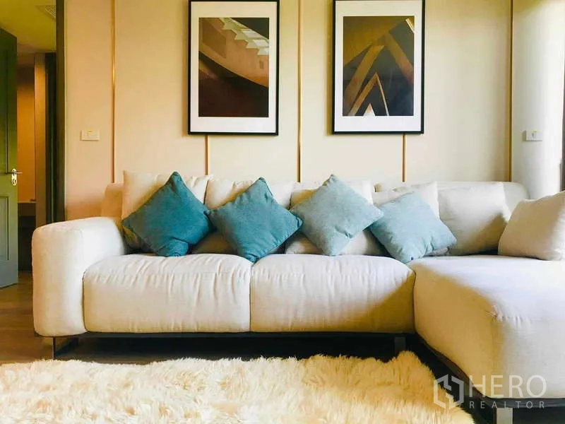 Condominium for rent - Bright living room with cream L-shaped sofa, blue cushions, framed artwork and a plush rug.
